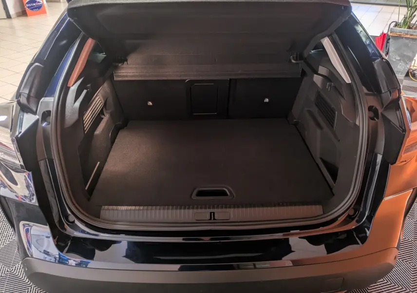 Coffre ouvert vu de l'arrière d'une Citroën C4 hybride 2025 bleu nuit, montrant un espace de chargement spacieux.