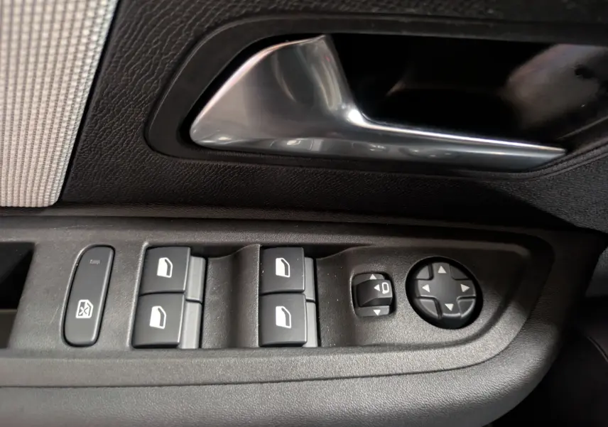Gros plan sur les commandes de vitres et rétroviseurs côté conducteur d'une Citroën C4 Hybride 145 e-DCS6 Max, intérieur noir.