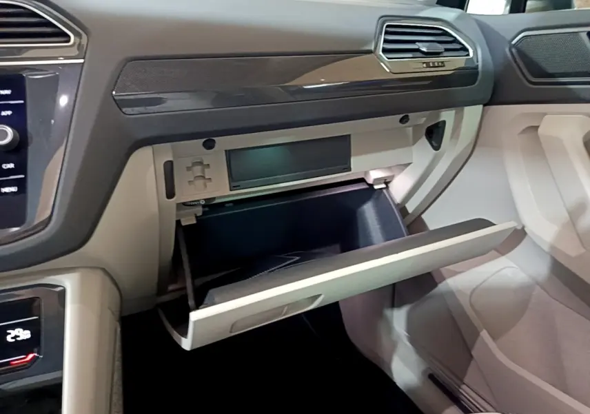 Vue intérieure côté passager du tableau de bord gris clair du Volkswagen Tiguan 2022 avec boîte à gants ouverte.