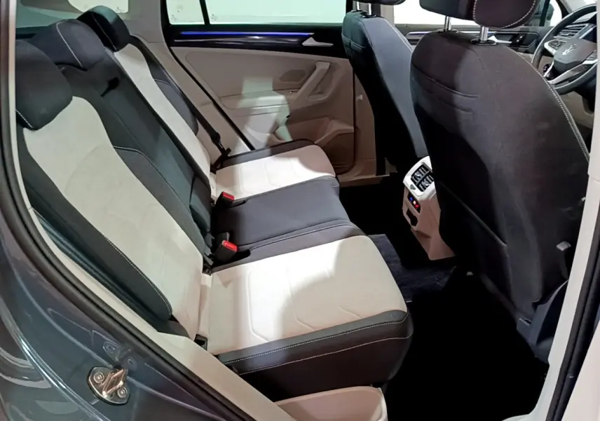 Vue intérieure côté gauche des sièges arrière bicolores noir et beige du Volkswagen Tiguan 2022, avec console centrale visible.