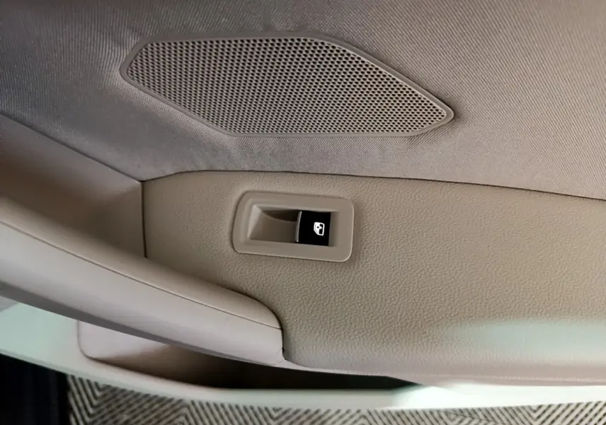 Détail du plafonnier beige avec bouton d'ouverture du hayon du Volkswagen Tiguan gris clair, vue intérieure.