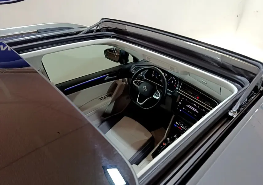 Vue plongeante sur l'intérieur clair du Volkswagen Tiguan gris clair 2022, avec toit ouvrant panoramique ouvert.