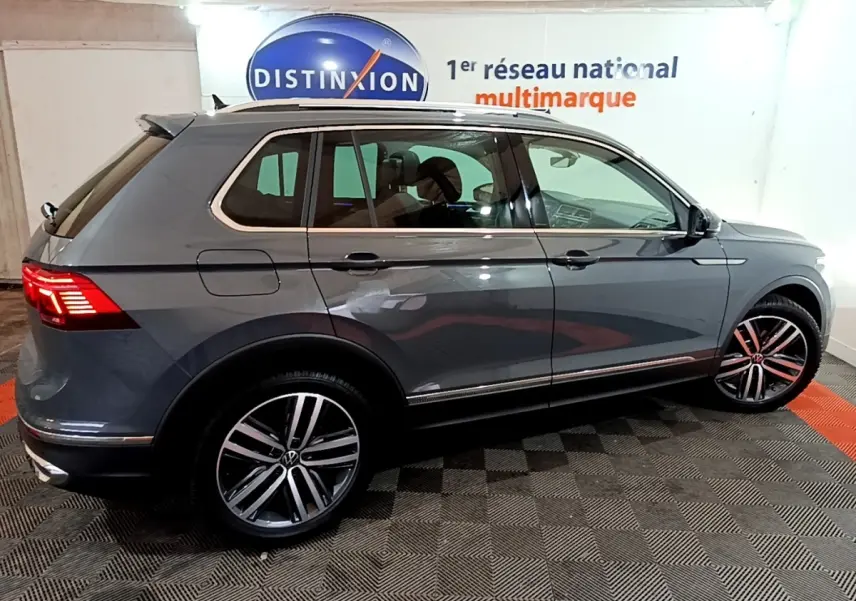 Vue de profil côté droit d’un Volkswagen Tiguan gris clair 2022 avec jantes alliage et feux arrière LED allumés.