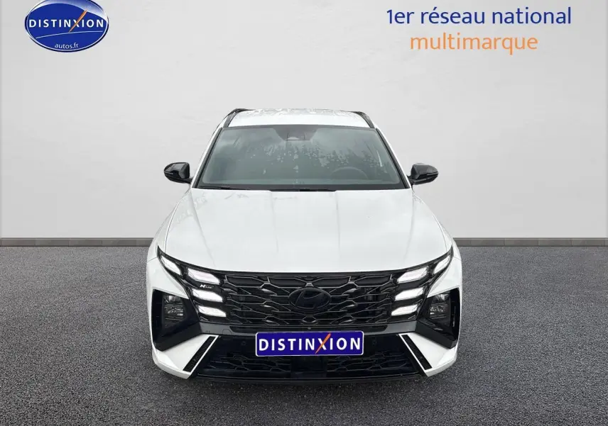 Vue frontale du Hyundai Tucson blanc sérénité avec calandre noire et feux LED distinctifs en ligne.