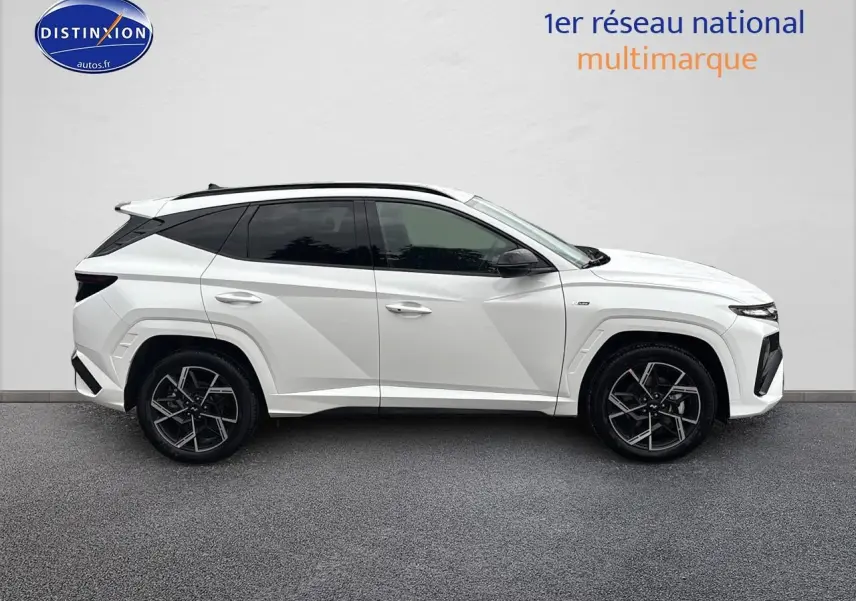 Vue de profil côté gauche du Hyundai Tucson blanc sérénité avec jantes alliage noires et toit panoramique.