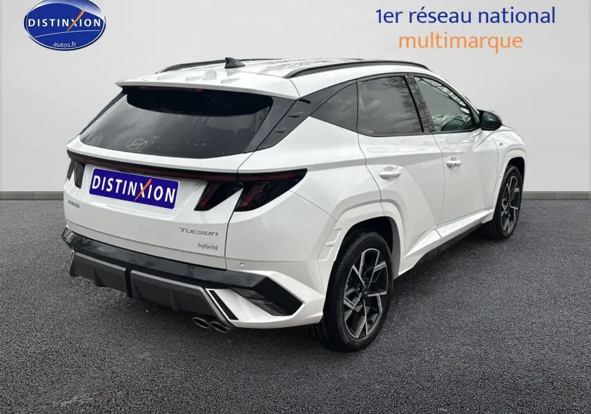 Vue 3/4 arrière droite d'un Hyundai Tucson blanc sérénité avec jantes alliage 19 et détails N Line noirs.