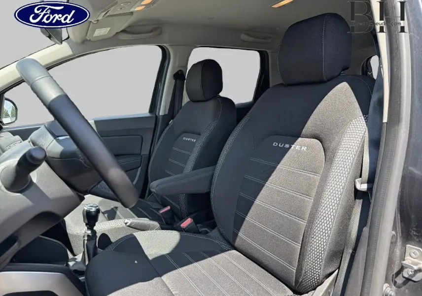 Intérieur du Dacia Duster 2020, vue côté conducteur, sièges noirs avec logo Duster brodé, volant multifonction visible.