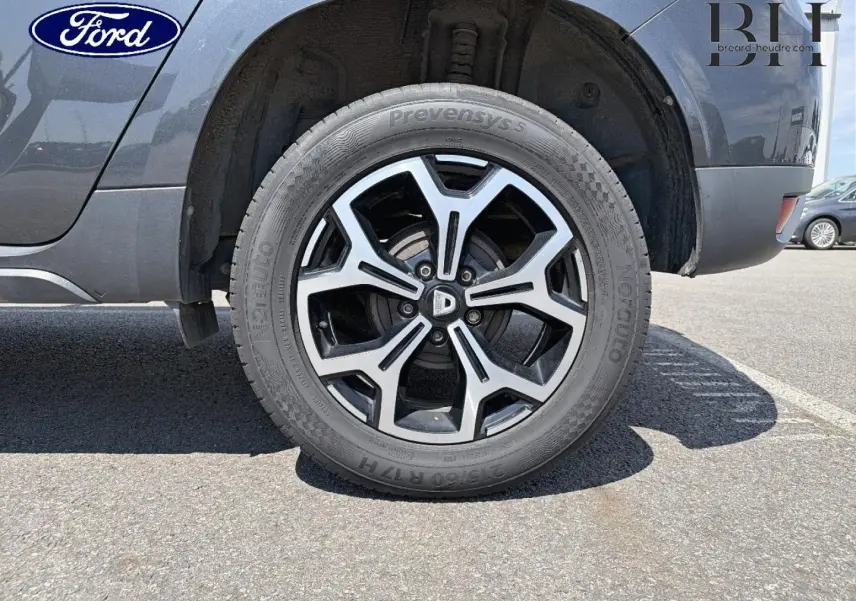 Gros plan sur la roue arrière droite du Dacia Duster gris Comète métallisé avec jante alliage distinctive.