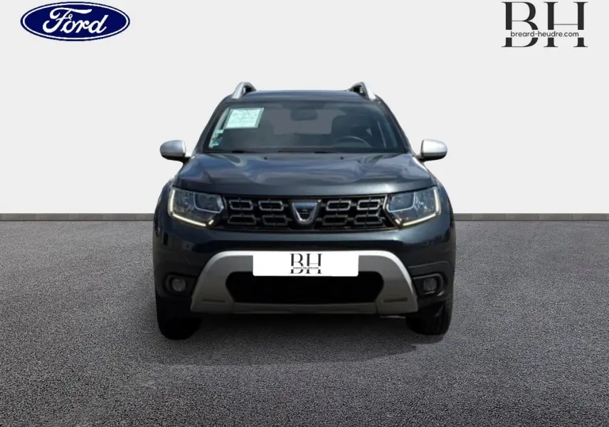 Vue avant du Dacia Duster gris Comète métallisé avec calandre noire et protections argentées sur pare-chocs.