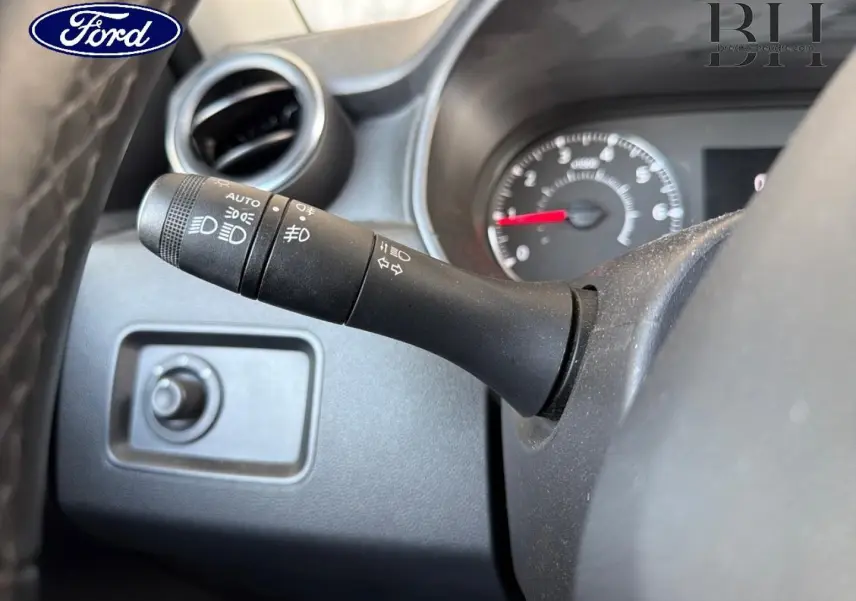Manette de commande des phares en gros plan à gauche du volant, intérieur noir d’un véhicule Ford.