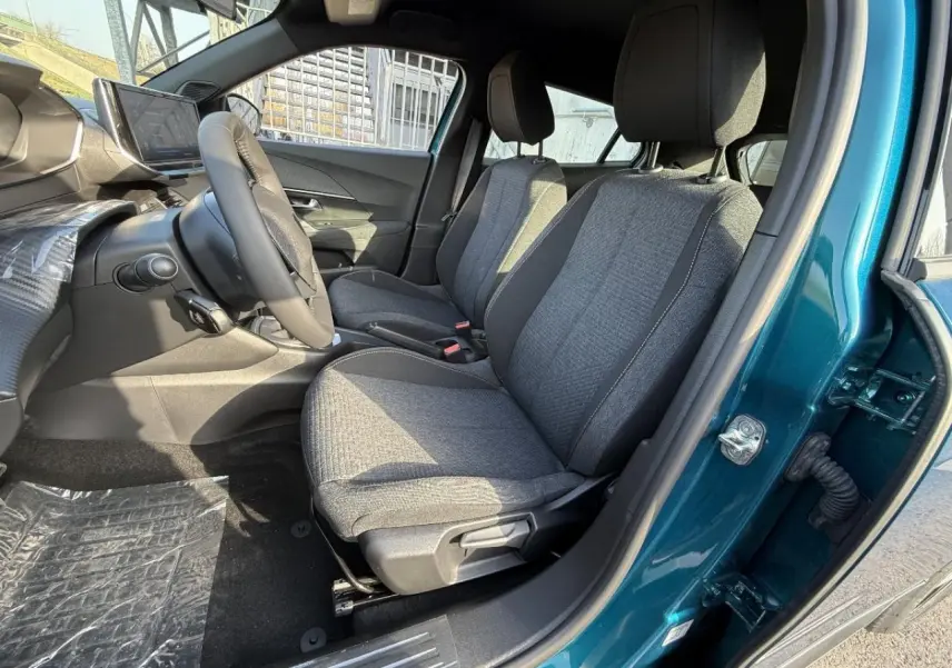 Vue intérieure côté conducteur du Peugeot 2008 2025 bleu obsession, montrant les sièges tissus gris et le volant.