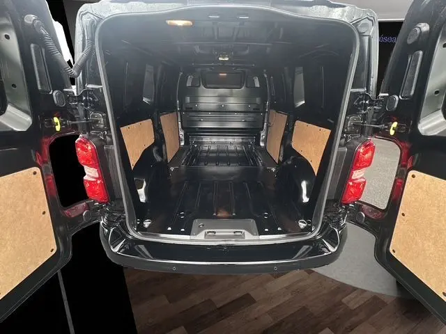 Vue arrière ouverte du Citroën Jumpy noir 2025, montrant l'espace de chargement vide avec panneaux latéraux en bois.