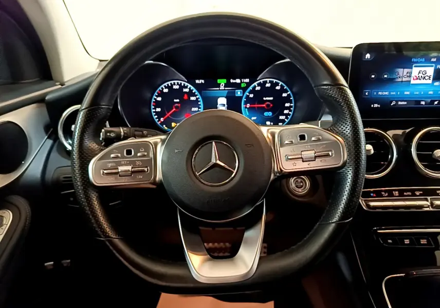 Vue centrée sur le volant cuir et alu de la Mercedes GLC 300 E AMG Line 2021 avec tableau de bord numérique et écran tactile.