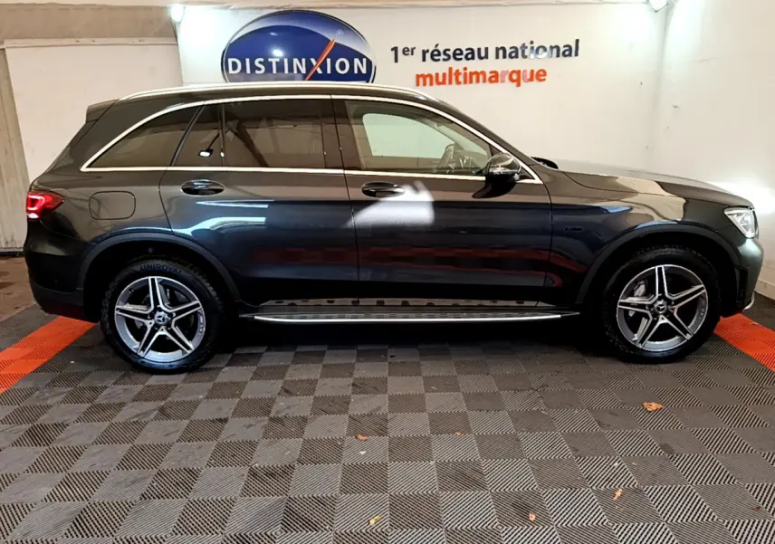 Vue latérale droite d'un Mercedes GLC 300 E AMG Line gris foncé avec jantes alliage et rails de toit chromés.
