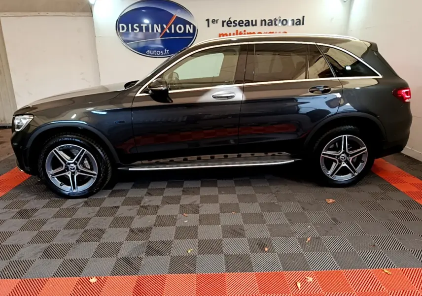 Profil droit d'un Mercedes GLC 300 E AMG Line gris foncé avec jantes alliage et vitres teintées en intérieur showroom.