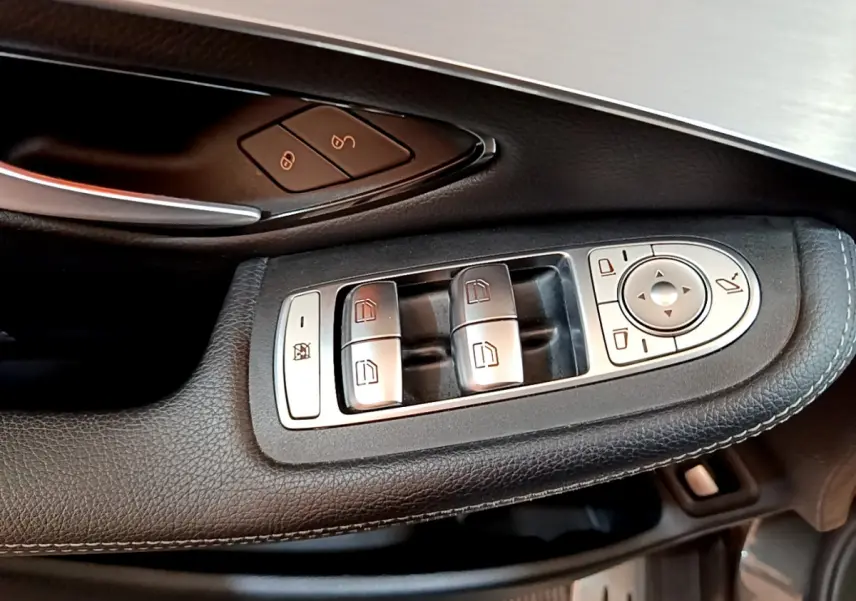 Gros plan sur les commandes de lève-vitres et rétroviseurs côté conducteur d'un Mercedes GLC 300 E AMG Line gris foncé.