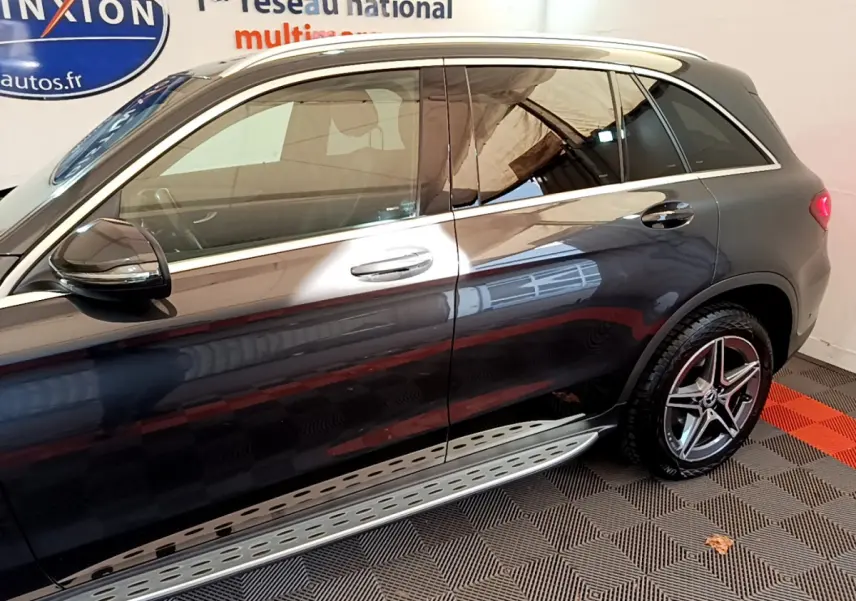 Vue latérale droite d'un Mercedes GLC 300 E AMG Line gris foncé avec jantes étoile et marchepied aluminium.