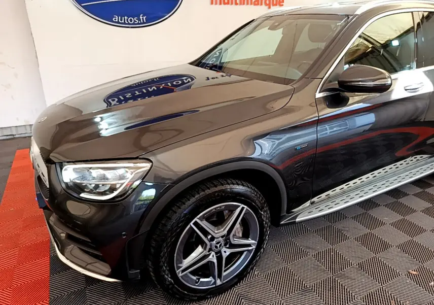 Vue 3/4 avant droit d'un Mercedes GLC 300 E AMG Line gris foncé avec jantes alliage et badge hybride visible sur la portière.