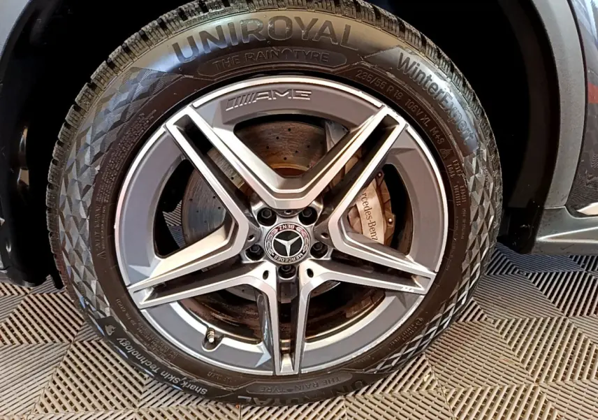 Gros plan sur la jante AMG gris foncé avec logo Mercedes et pneu hiver Uniroyal sur un Mercedes GLC hybride rechargeable.