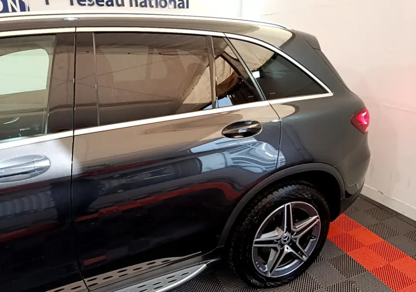 Vue côté droit arrière d'un Mercedes GLC 300 E AMG Line gris foncé avec jante alliage et feux LED allumés.