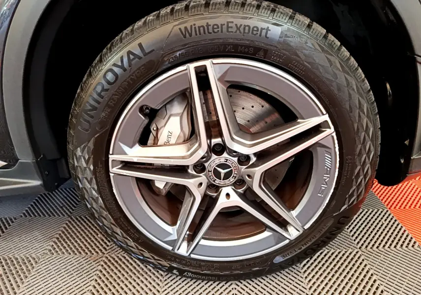 Gros plan sur la roue avant droite du Mercedes GLC 300 E AMG Line gris foncé avec jante AMG et pneu hiver Uniroyal.