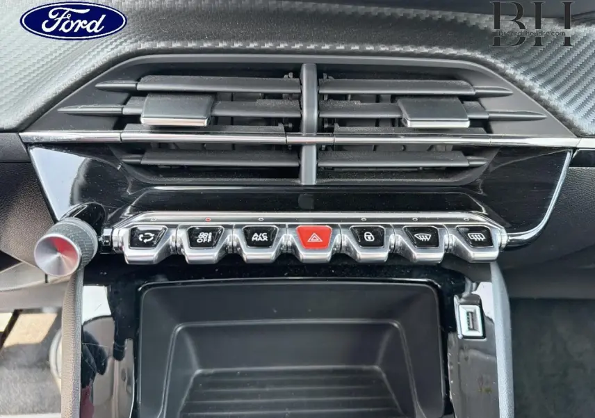 Tableau de bord avec commandes en rangée et aérateurs, intérieur noir brillant d'une Peugeot 208 gris Platinium.
