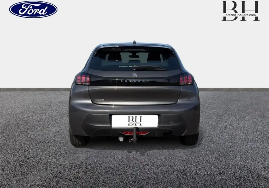 Vue arrière d'une Peugeot 208 gris Platinium avec attelage visible, sur sol goudronné et fond blanc.