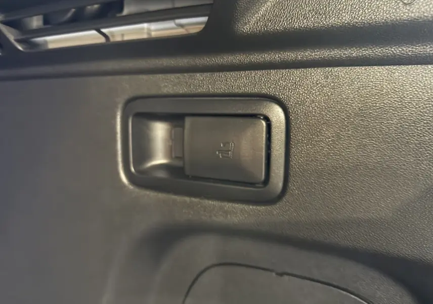 Gros plan sur la commande de rabattement des sièges arrière dans l’habitacle noir d’un Opel Grandland X hybride blanc.