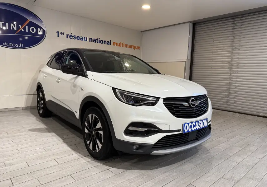 Opel Grandland X blanc en 3/4 avant droit, toit noir, calandre noire et jantes alliage bicolores.