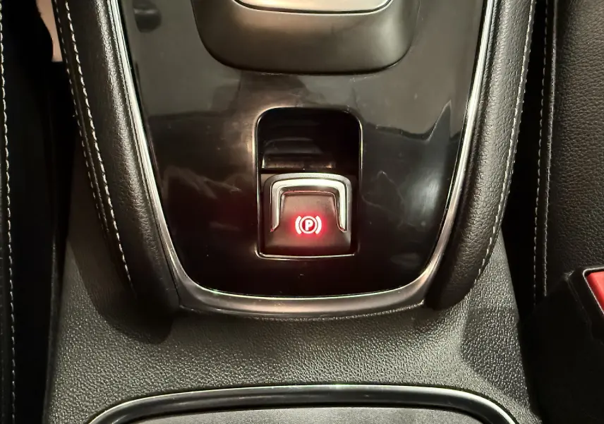 Gros plan sur le bouton de frein à main électronique rouge dans la console centrale noire de l’Opel Grandland X hybride 2021.