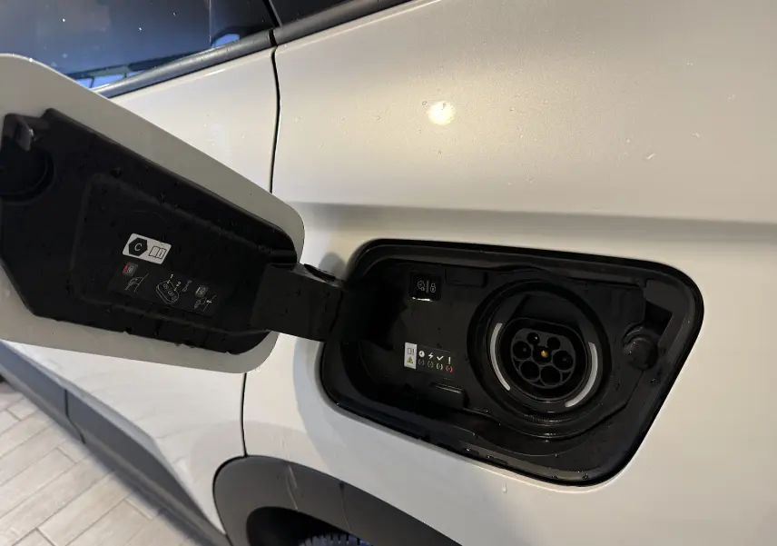 Prise de recharge ouverte côté gauche d’un Opel Grandland X blanc hybride rechargeable, détail du port de charge.