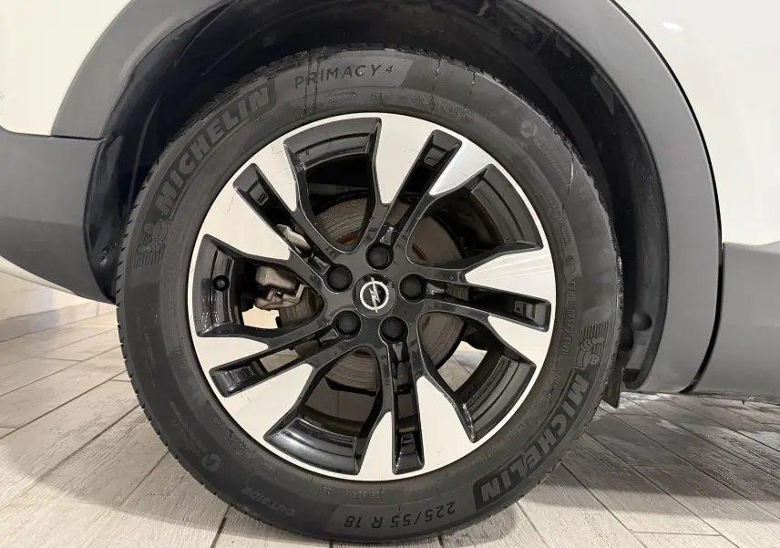 Gros plan sur la roue avant gauche d’un Opel Grandland X blanc avec jante alliage bicolore et pneu Michelin.