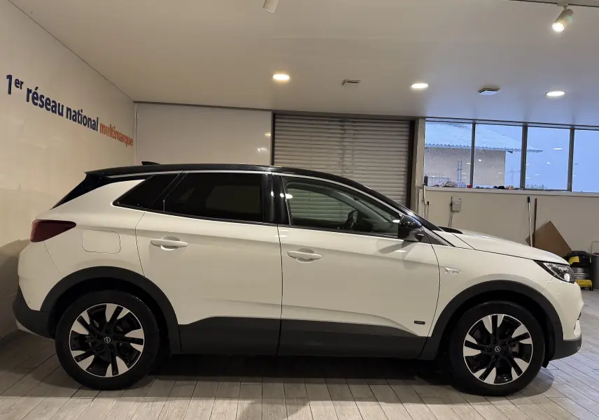 Vue latérale droite d'un Opel Grandland X blanc avec toit noir, jantes bicolores et détails noirs contrastants.