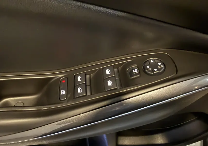 Gros plan sur les commandes de lève-vitres et réglages des rétroviseurs sur la porte intérieure noire d’un Opel Grandland X.
