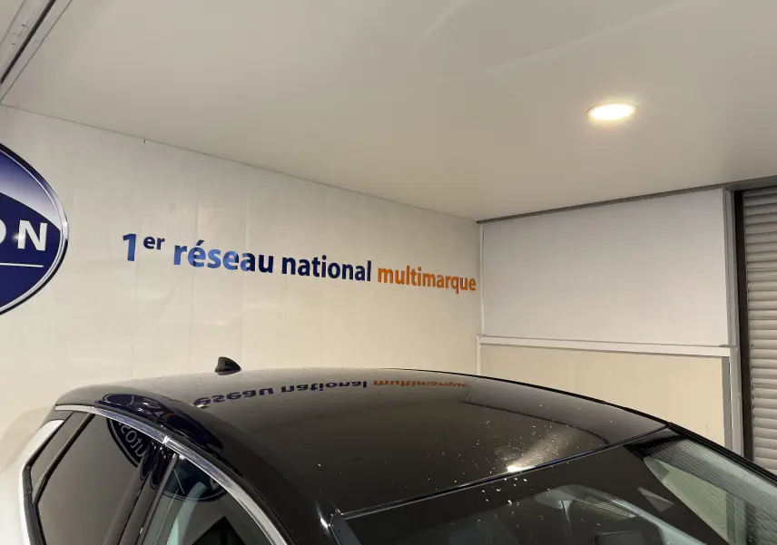 Vue partielle en plongée du toit noir brillant et des vitres latérales d’un Opel Grandland X blanc stationné en intérieur.