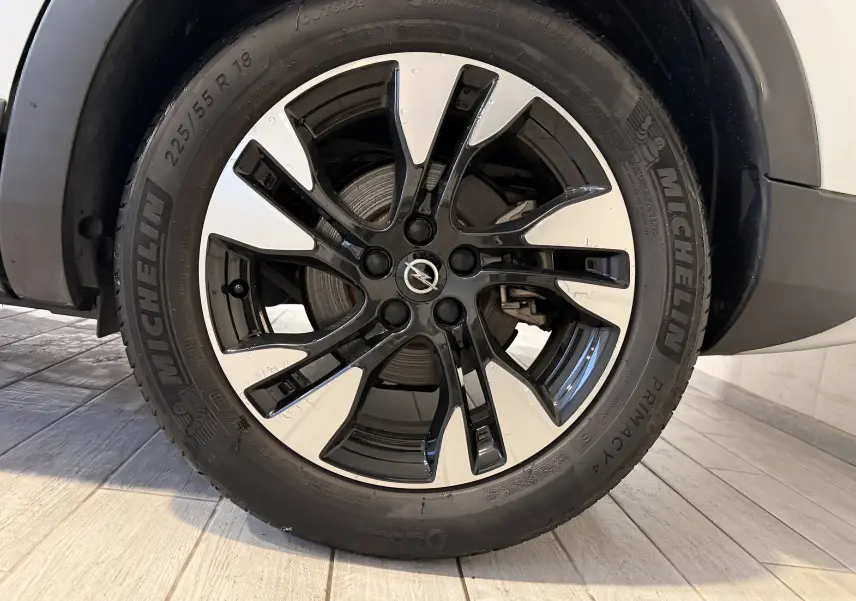 Gros plan sur la roue avant droite d’un Opel Grandland X blanc, jante alliage bicolore noir et argent.