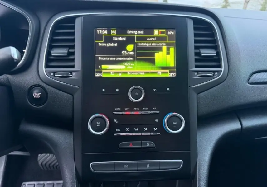 Vue rapprochée du tableau de bord de la Renault Mégane Business, avec écran tactile et commandes de climatisation.