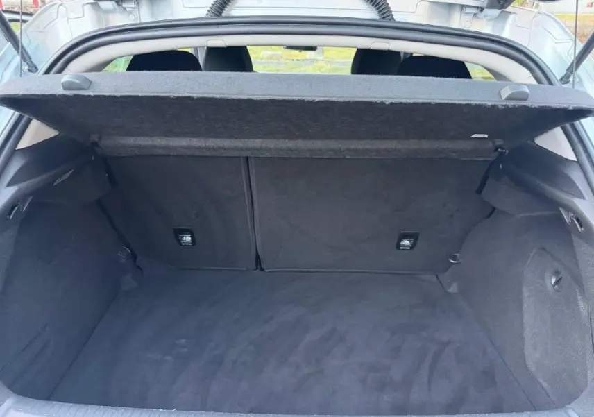 Coffre ouvert vu de l'arrière d'une Renault Mégane Business gris alu, montrant un espace de chargement propre et spacieux.