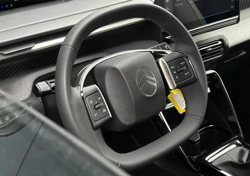 Vue rapprochée du volant noir de la Citroën C3 2025 avec commandes intégrées et écran tactile central visible.