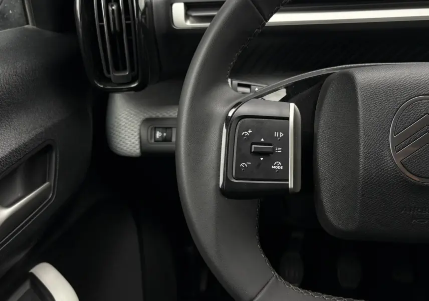 Gros plan sur le volant noir de la Citroën C3 Turbo 100 Max 2025, avec commandes intégrées à gauche et logo central.