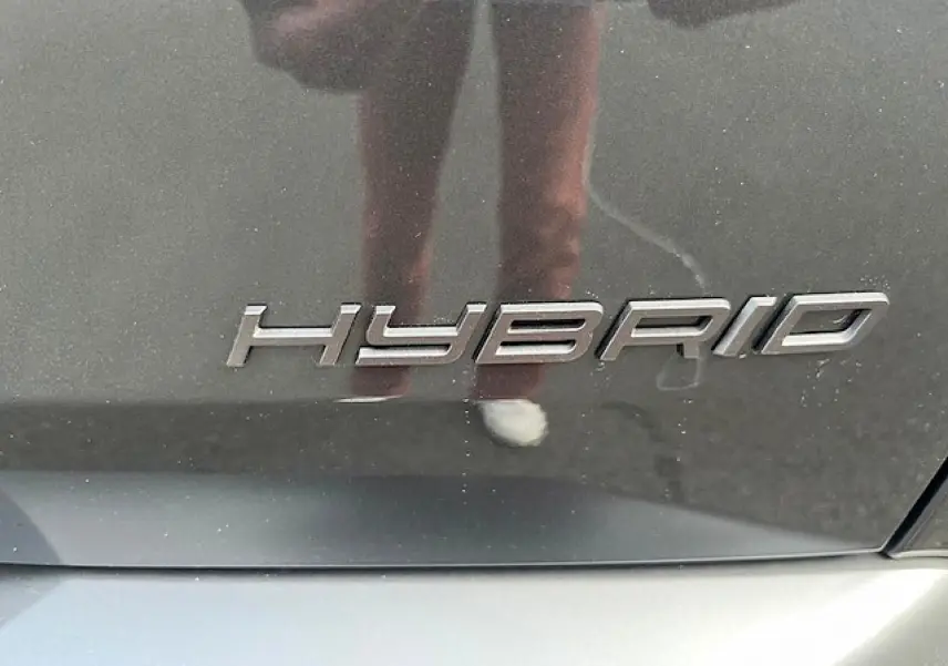 Gros plan sur l’inscription "HYBRID" en chrome sur la carrosserie gris titane d’un Peugeot 3008.