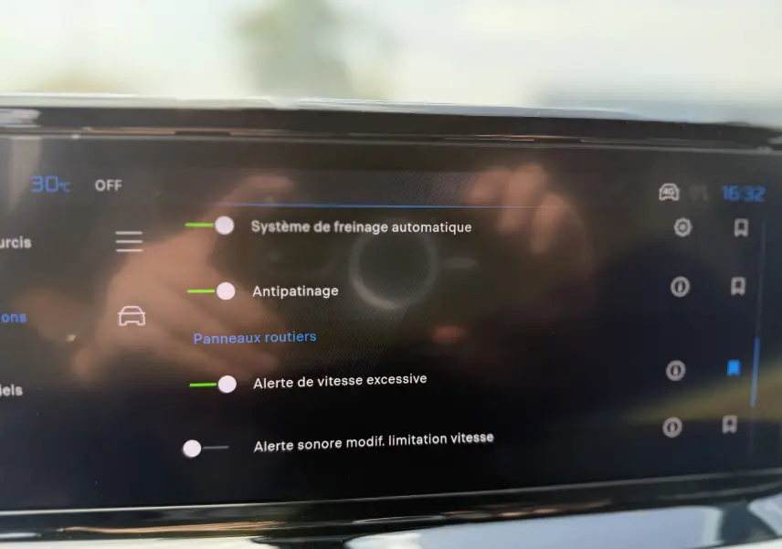 Écran tactile du tableau de bord de la Peugeot 208 Hybrid 145 GT en gris Artense montrant les options d'aide à la conduite.