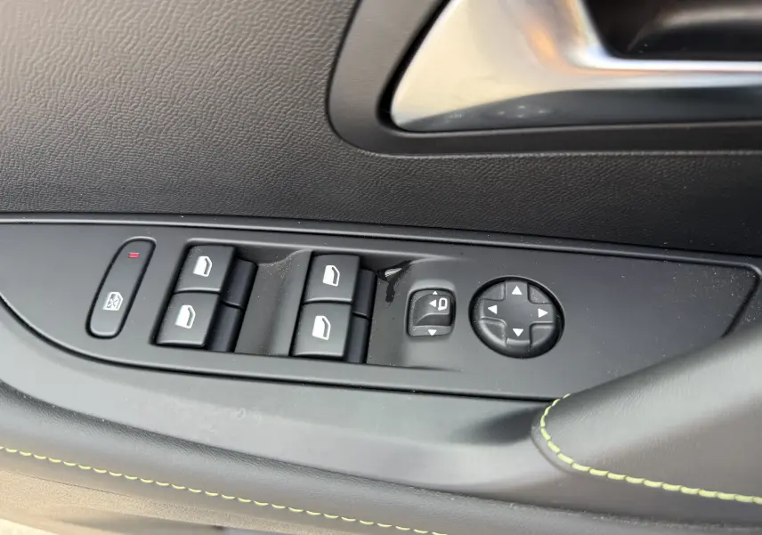 Gros plan sur les commandes de lève-vitres et réglage des rétroviseurs côté gauche d'une Peugeot 208 Hybrid 145 GT gris Artense.