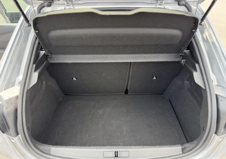 Vue ouverte du coffre spacieux et noir d'une Peugeot 208 Hybrid 145 GT gris Artense de 2024.