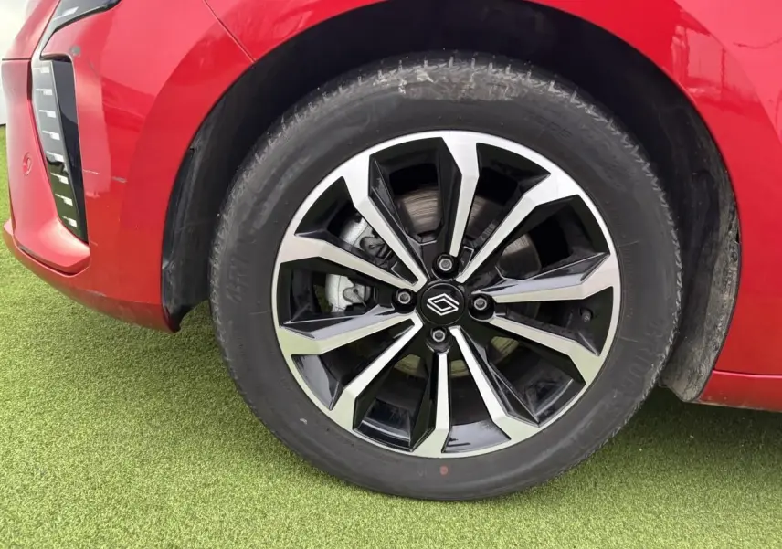 Gros plan sur la roue avant gauche de la Renault Clio V rouge flamme métal avec jante alliage noire et argent.