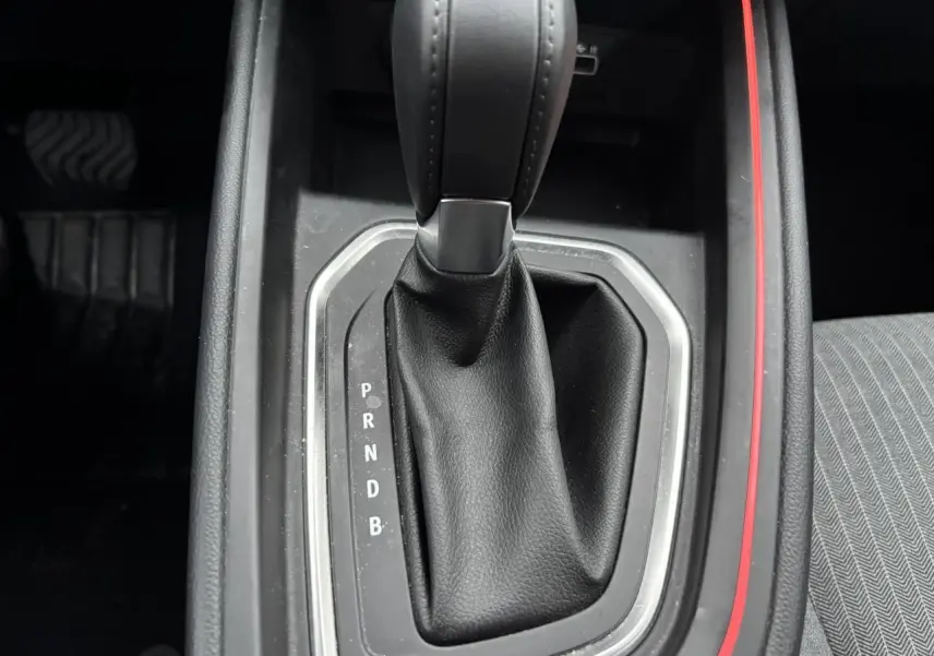 Le levier de vitesses automatique noir de la Renault Clio V hybride, avec surpiqûres et contour argenté, vu de dessus.