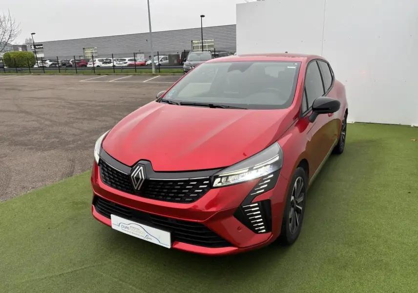 Renault Clio V hybride rouge flamme vue 3/4 avant droit, avec feux LED et calandre noire distinctive.
