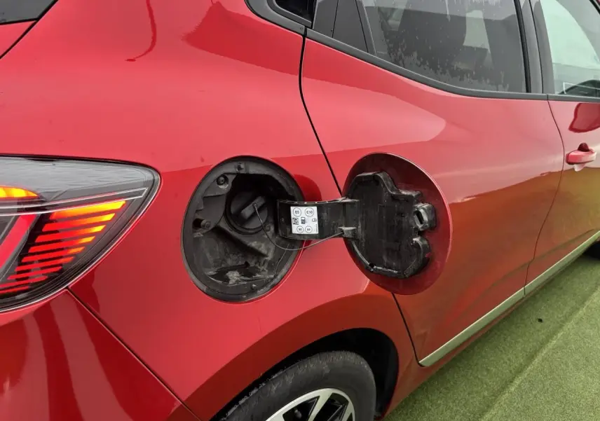 Vue latérale droite de la Renault Clio rouge flamme avec trappe de carburant ouverte et feu arrière allumé.