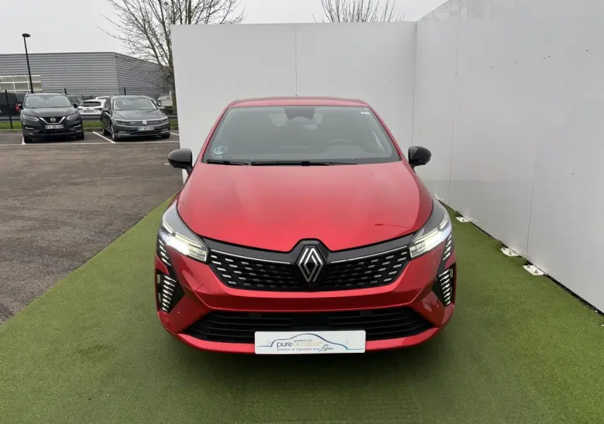 Vue avant d'une Renault Clio V rouge flamme métallisée avec calandre noire et feux LED allumés.