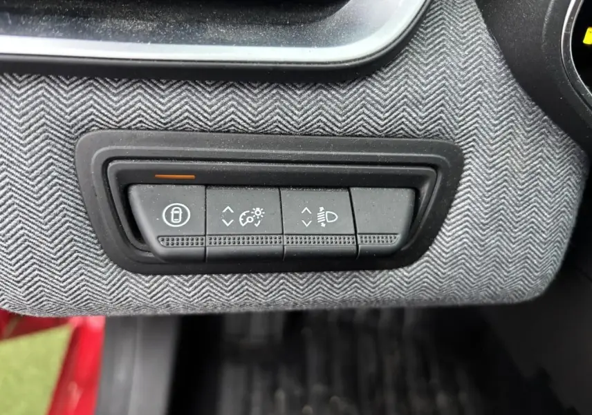 Gros plan sur les commandes d'éclairage et verrouillage sur la planche de bord gris chiné de la Renault Clio rouge flamme.